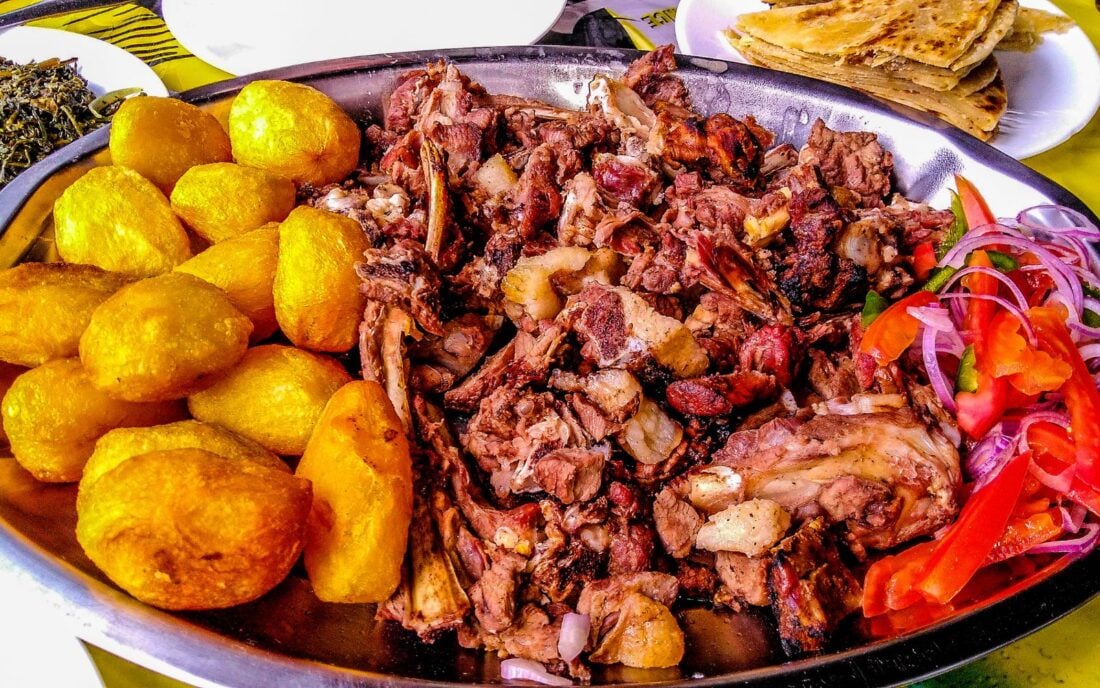 Sharing a platter of a traditional Kenyan dish, Nyama choma, and accompaniments of kachumbari salad, sukuma wiki, chapati, and roast potatoes