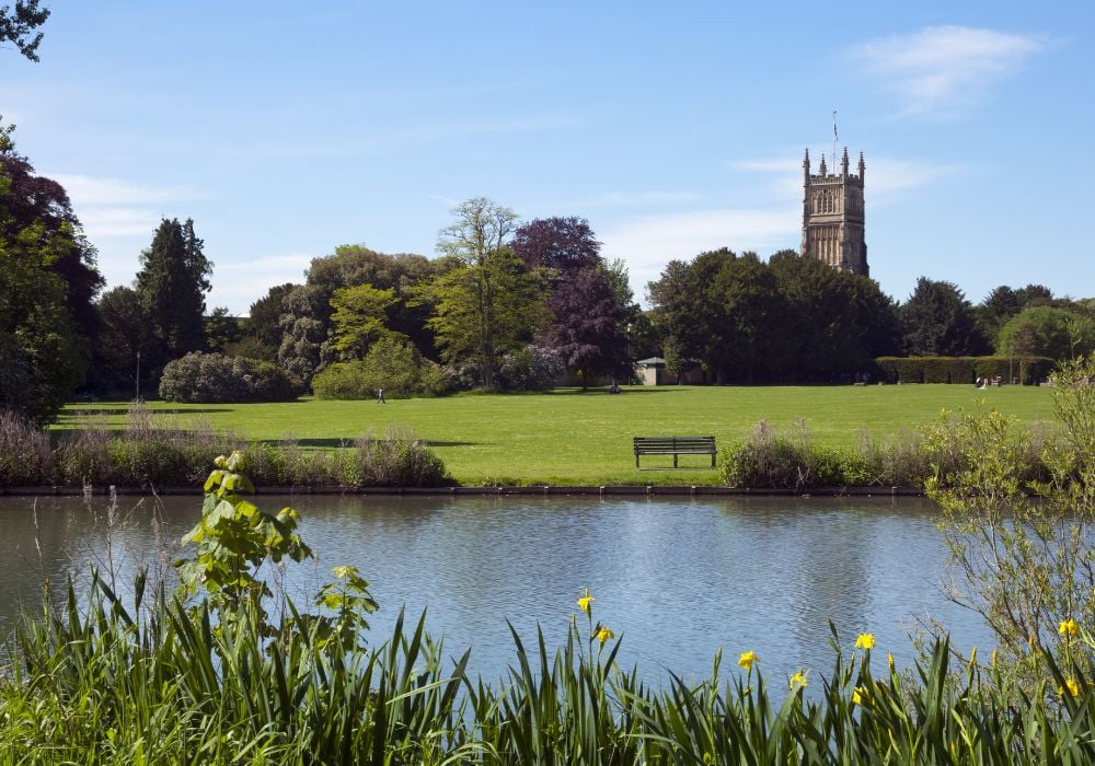 cirencister park in the cotswolds with the river, flowers green grass and church
