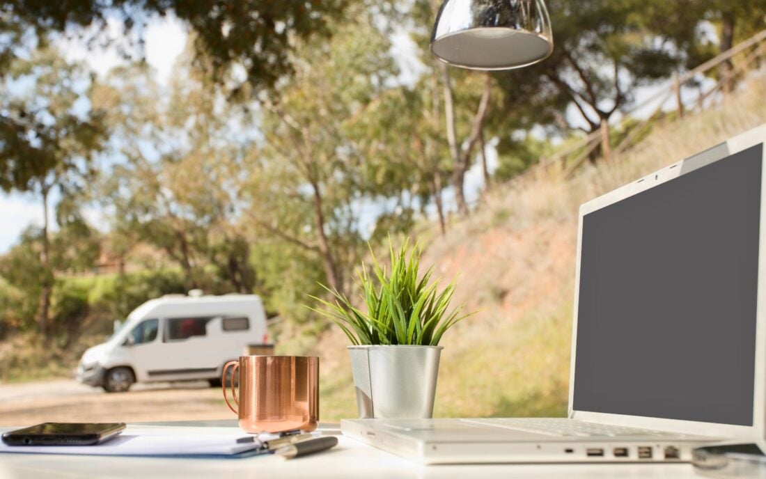 Outdoor work office with a computer, cellphone, and some digital nomad essentials.