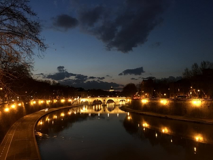 walking across the river at night in rome