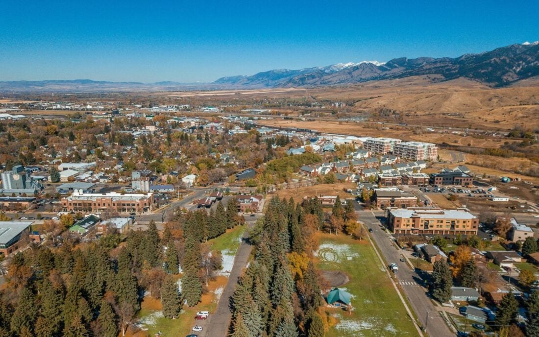 An aerial view of the brightly colored autumn trees in Lindley Park and a view of downtown Bozeman, Montana.